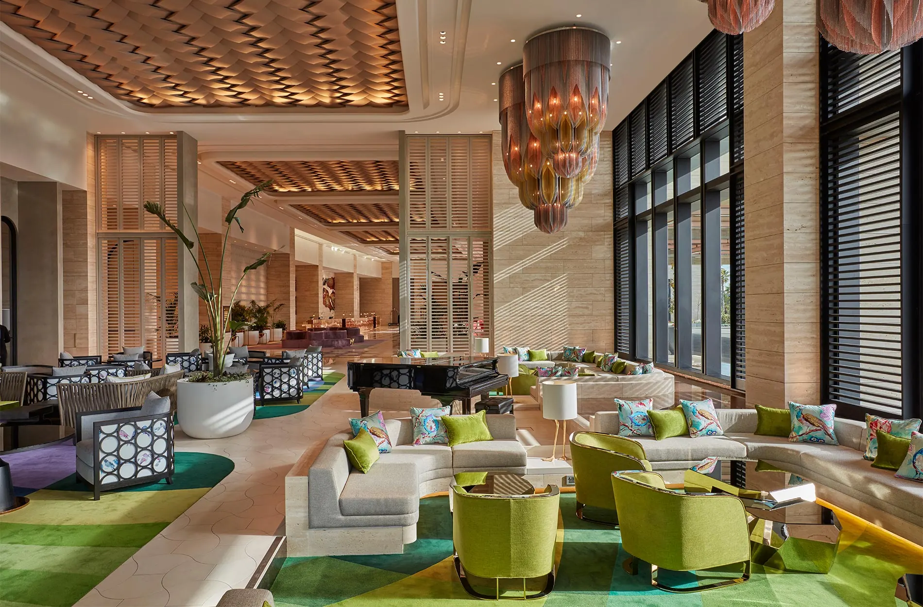 Hotel lobby with a custom patterned green carpet, grand piano and chandelier